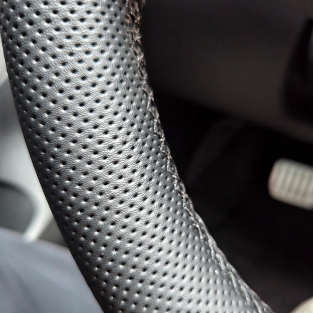 Close-up of the hand-stitched seam and perforated leather on the Tesla steering wheel cover