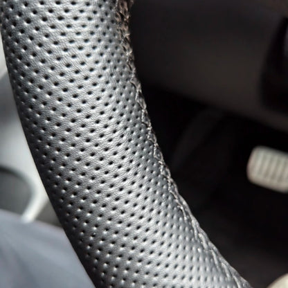 Close-up of the hand-stitched seam and perforated leather on the Tesla steering wheel cover